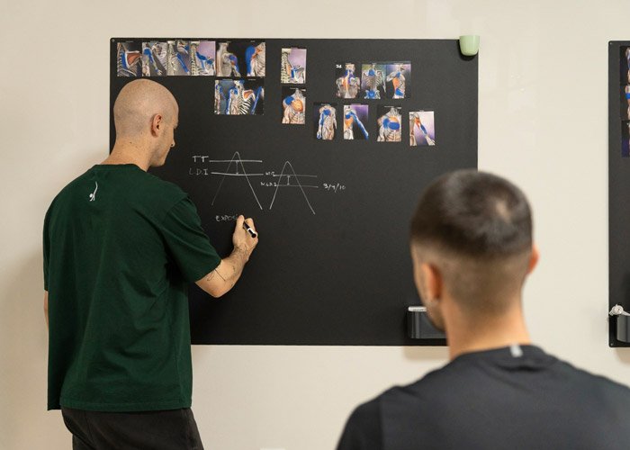 Fisioterapeuta explicando patología en pizarra Tratamientos fisioterapia Parets